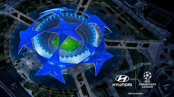 Flygvy över en fotbollsarena i form av UEFA Champions League-stjärnan, upplyst i blått, med Hyundai och UEFA Champions League Official Partner-logotyper