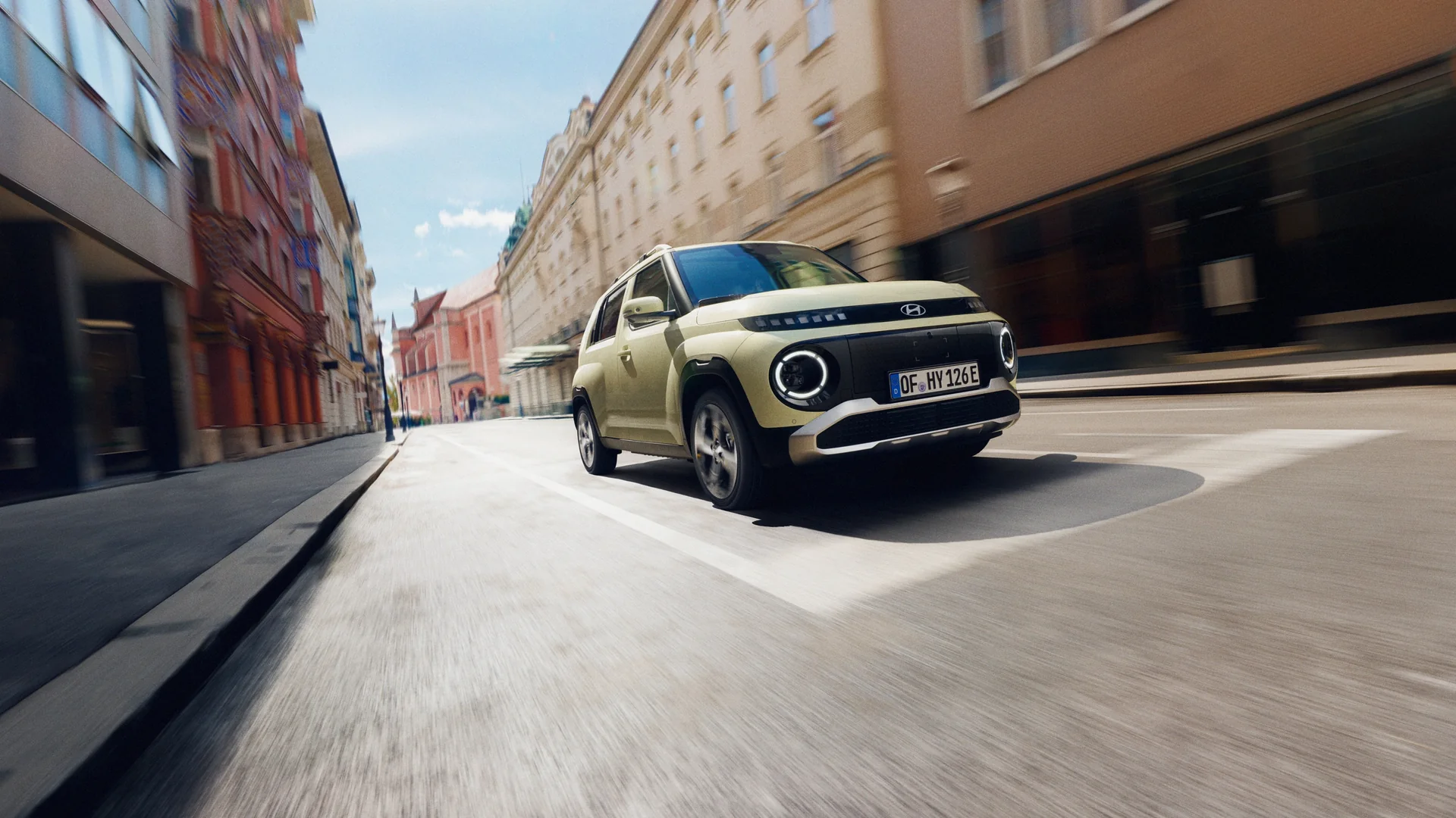 Hyundai INSTER körs på en stadsgata mellan kvarter i eftermiddagsljus