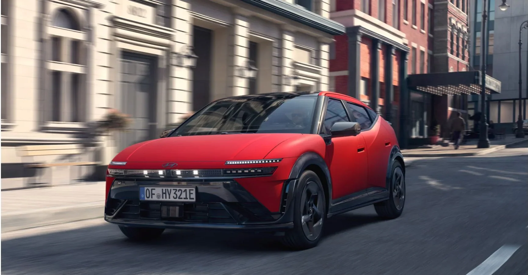 Röd Hyundai IONIQ 3 i stadsmiljö, fronten mot kameran under körning