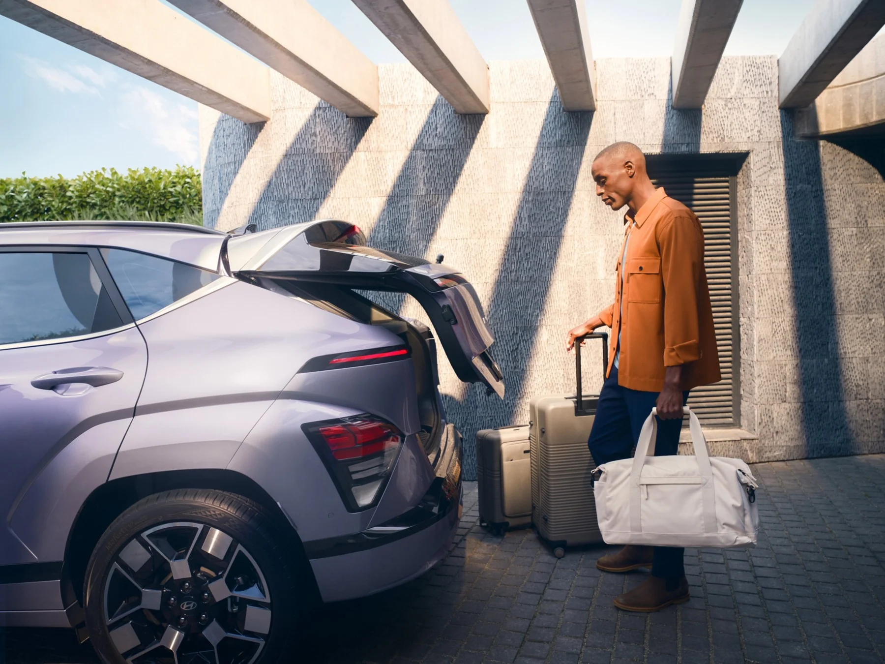 Person med resväskor vid den öppna bakluckan på Hyundai KONA Electric