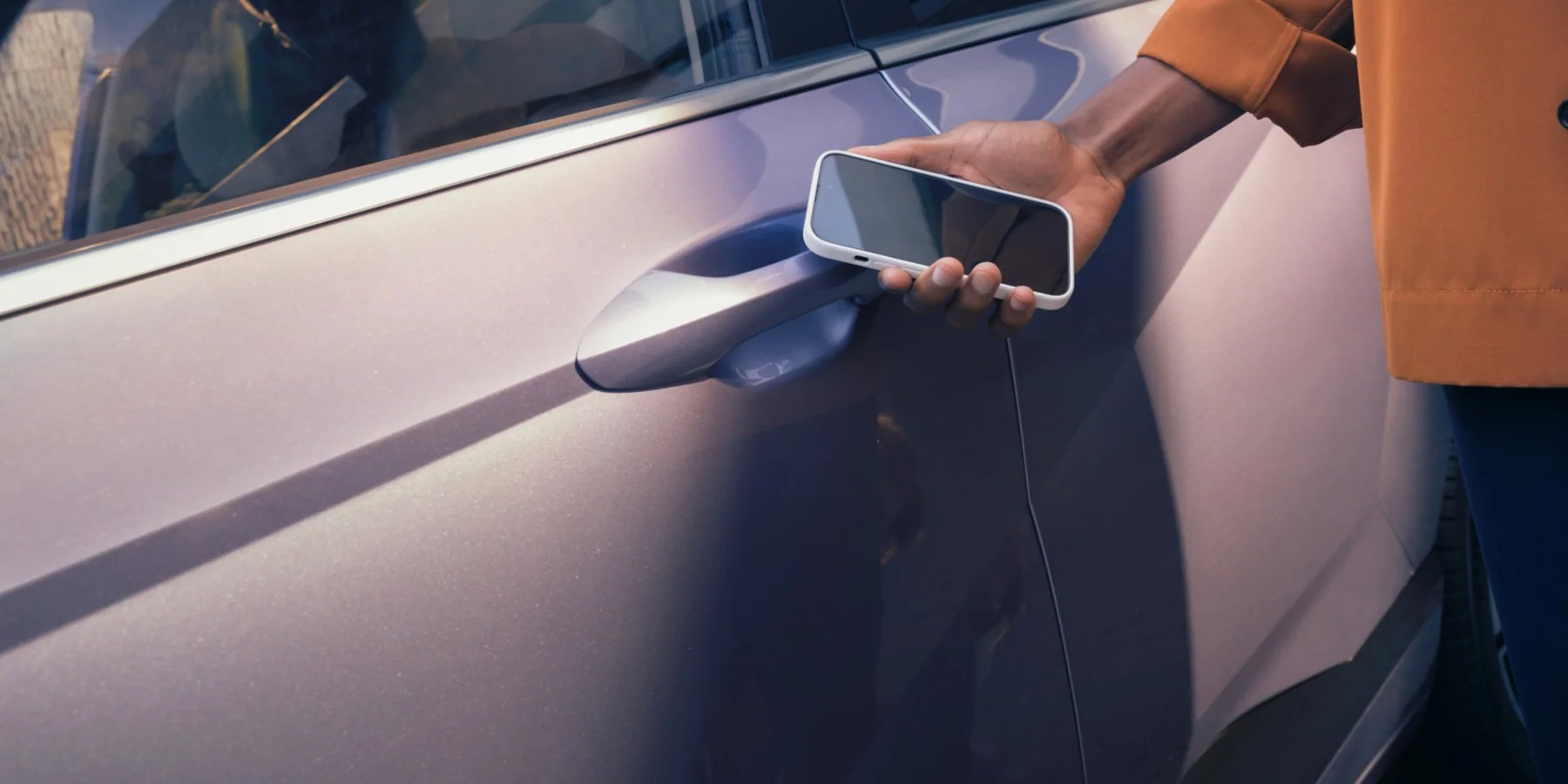 Hand med smartphone vid dörrhandtaget på Hyundai KONA Electric