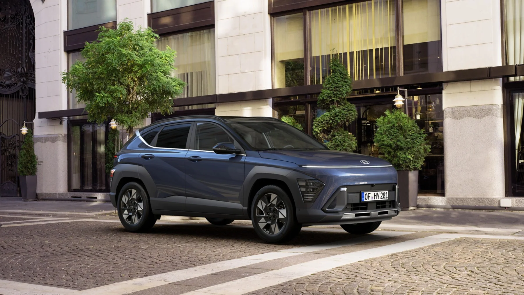 Hyundai KONA Electric i profil, parkerad vid en betongbyggnad i modern arkitektonisk miljö