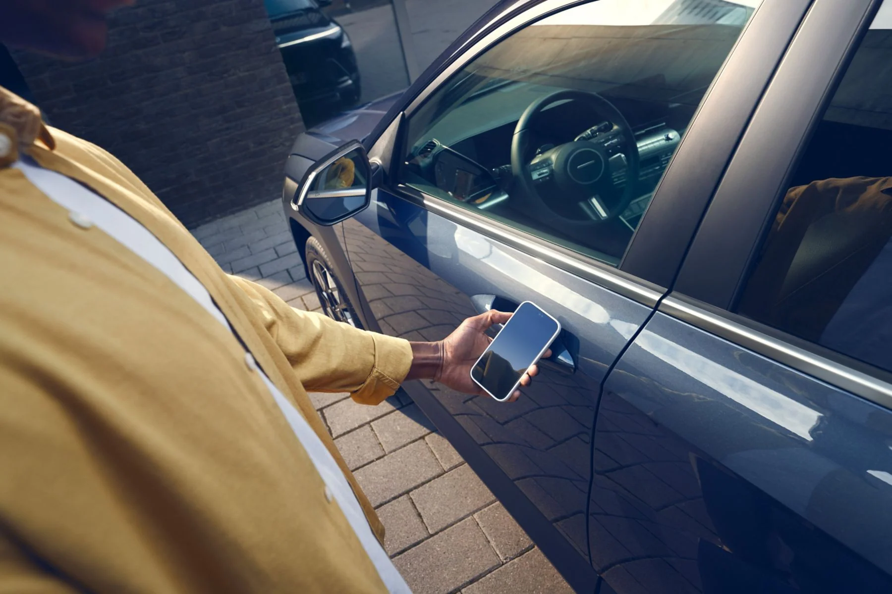 Hand med smartphone vid dörrhandtaget på Hyundai KONA Hybrid