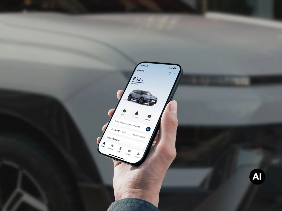 En hand håller en mobiltelefon med myHyundai-appen framför helt nya Hyundai BAYON N Line