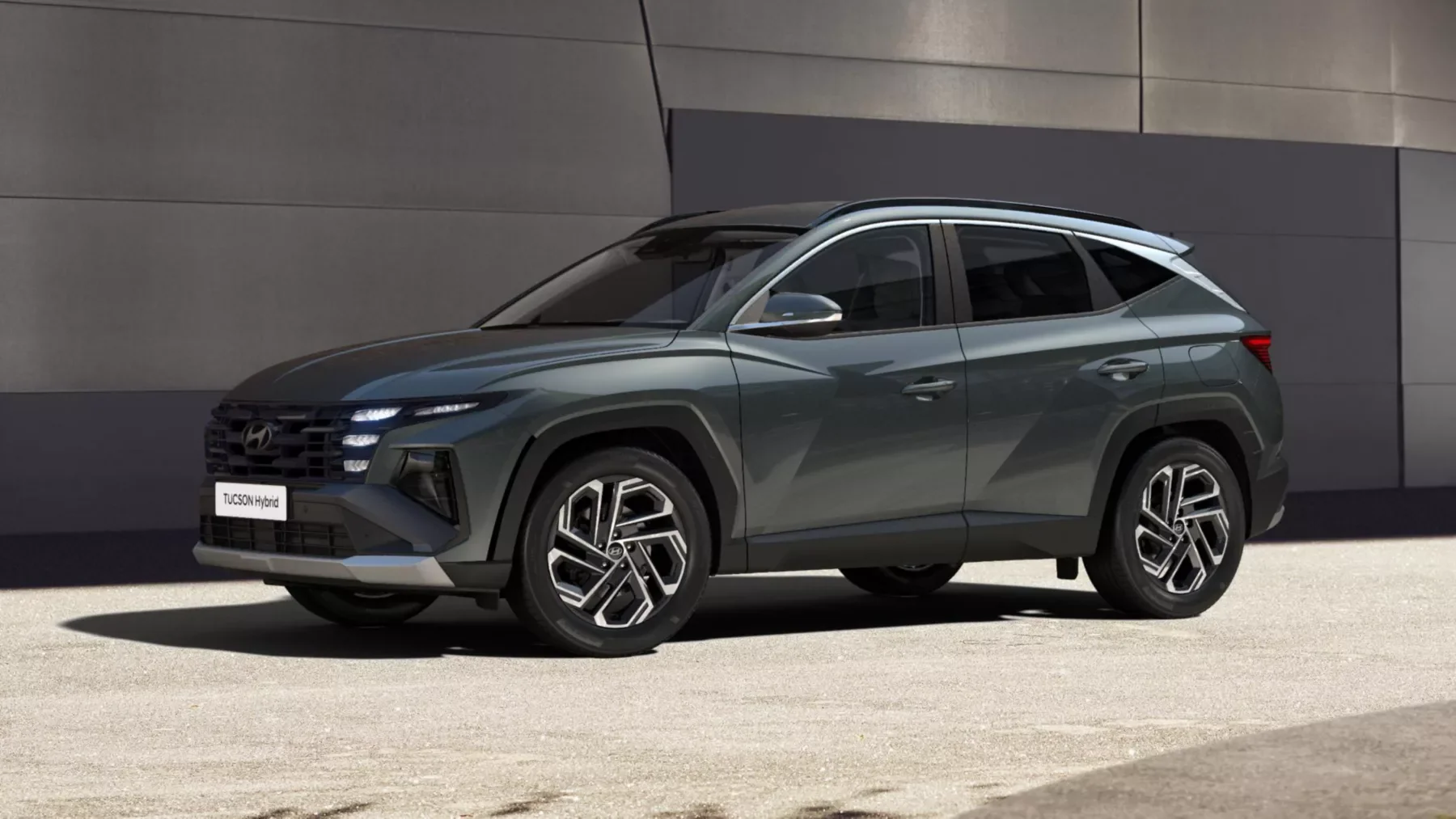 Hyundai TUCSON Hybrid i profil framför en grå fasad