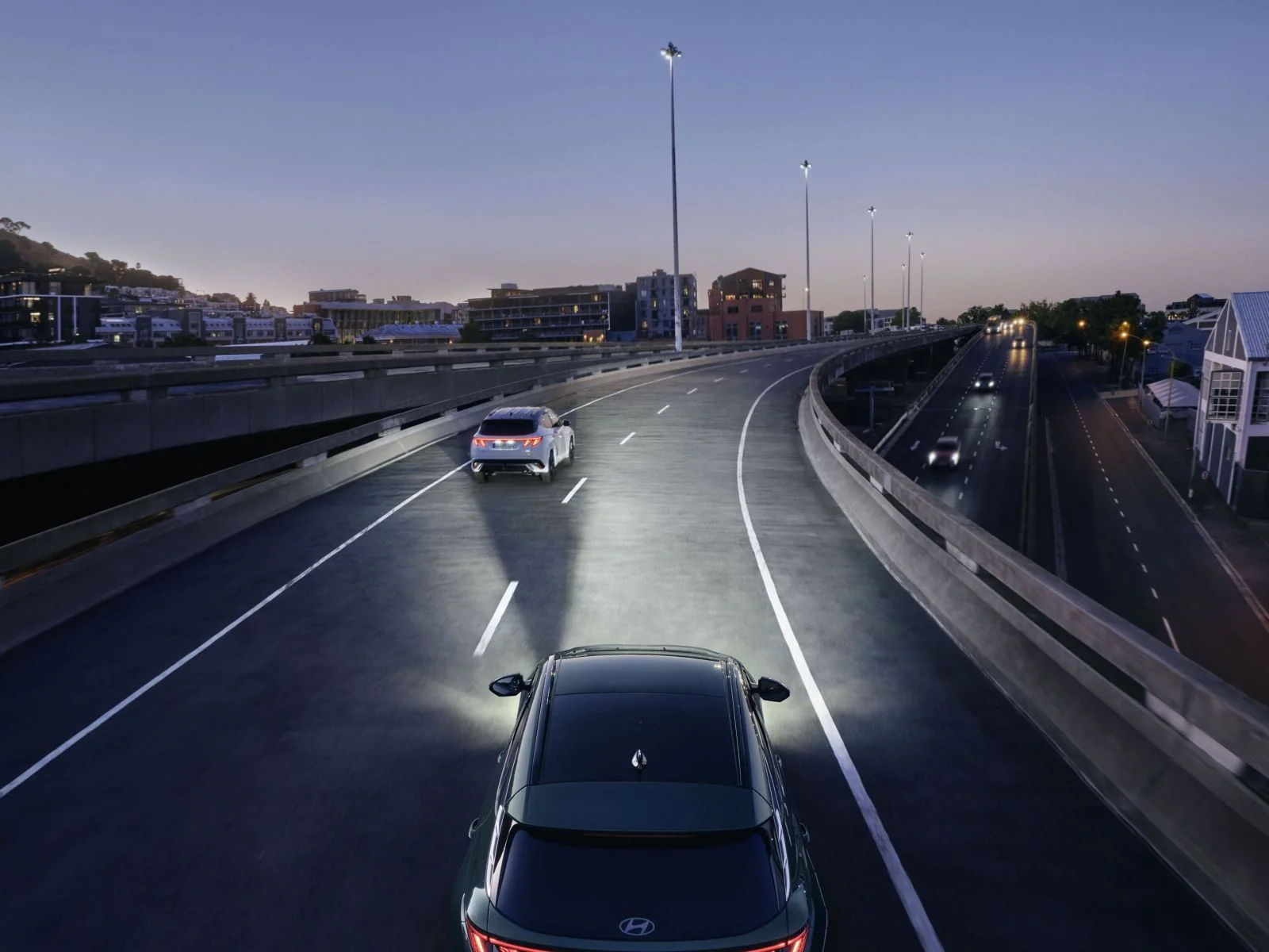Hyundai TUCSON Plug-in Hybrid kör i skymning med Intelligent Front-Lighting System tänt