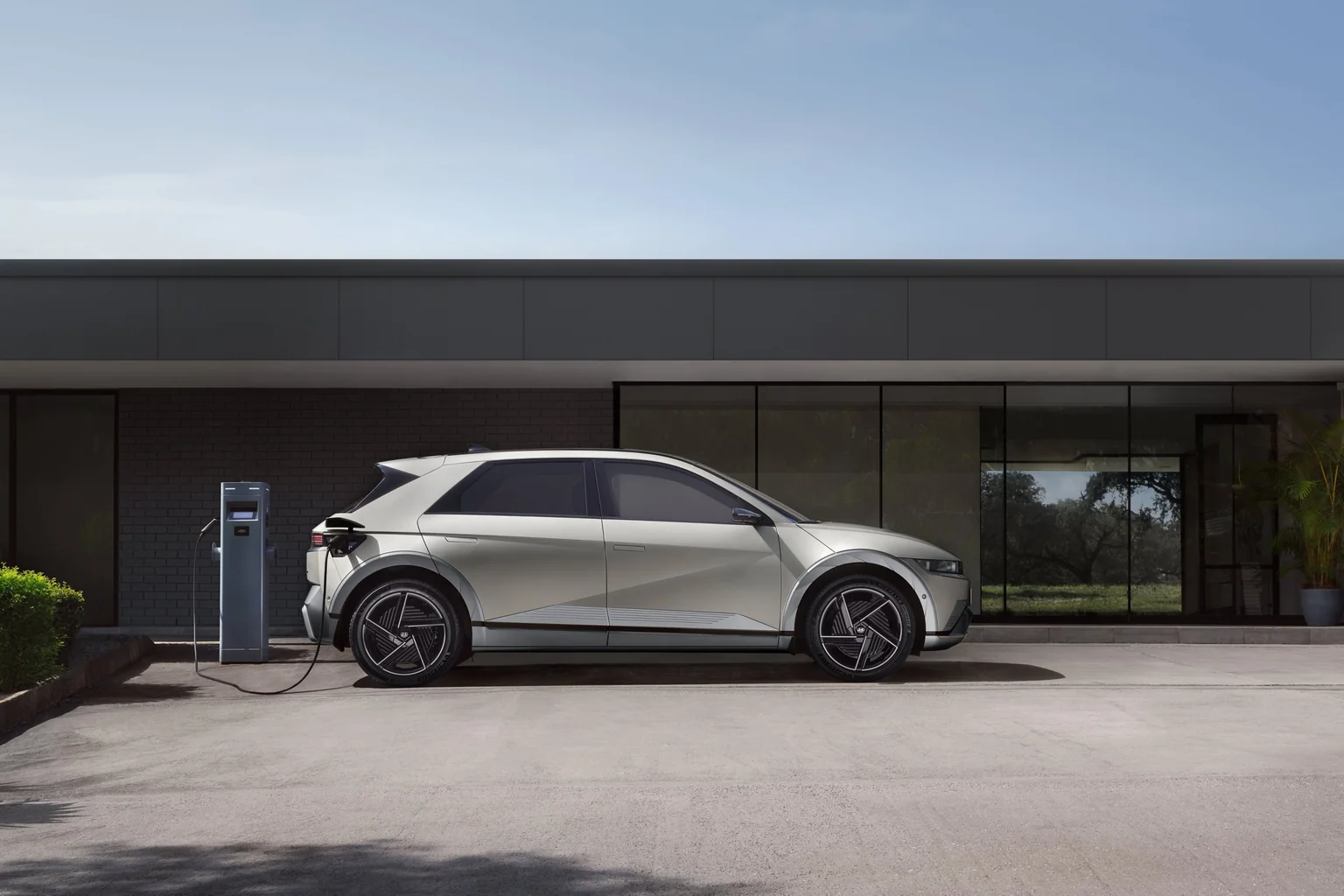 Hyundai IONIQ 5 ansluten till en laddstation utanför en byggnad
